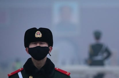 Un policía paramilitar con mascarilla monta guardia en la plaza de Tiananmén durante un día de alta polución en Pekín (China).