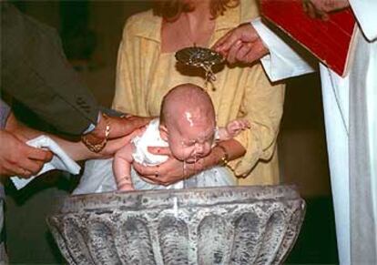 Rito del bautismo con el neófito en brazos de sus padrinos en una iglesia española.