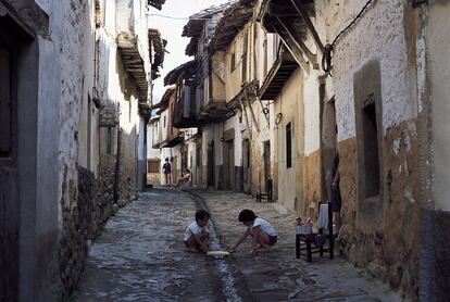 Unos niños juegan en una calle de Valverde de la Vera (Cáceres) que conserva su arquitectura tradicional basada en el uso de la piedra y la madera.