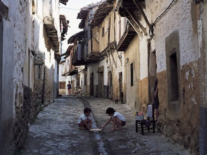 Unos niños juegan en una calle de Valverde de la Vera (Cáceres) que conserva su arquitectura tradicional basada en el uso de la piedra y la madera.