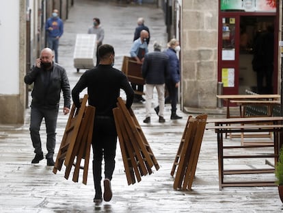 Un camarero trabaja en una terraza en una calle de Santiago de Compostela, donde se ha impuesto un máximo de cinco personas en las reuniones.