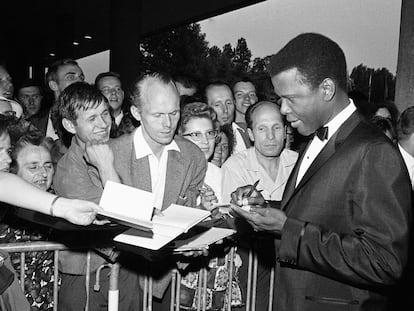 FILE - Sidney Poitier signs autographs before the opening of the 14th International Film Festival at the West Berlin congress hall on June 26, 1964 in Berlin.  Poitier, the groundbreaking actor and enduring inspiration who transformed how Black people were portrayed on screen, became the first Black actor to win an Academy Award for best lead performance and the first to be a top box-office draw, died Thursday, Jan. 6, 2022 in the Bahamas. He was 94. (AP Photo/Edwin Reichert, File)