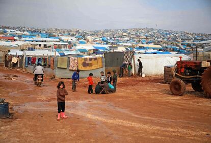 Los niños se reúnen en las afueras de sus refugios improvisados ​​después de una lluvia torrencial que afectó a un campamento de desplazados de la ciudad de Atme, cerca de la frontera con Turquía, en la provincia de Idlib (Siria).