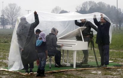 O artista Ai Weiwei (à direita) assiste à apresentação de piano da síria Nour Al Khizam no campo de refugiados situado na fronteira da Grécia com a Macedônia em 12 de março.