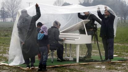 O artista Ai Weiwei (à direita) assiste à apresentação de piano da síria Nour Al Khizam no campo de refugiados situado na fronteira da Grécia com a Macedônia em 12 de março.