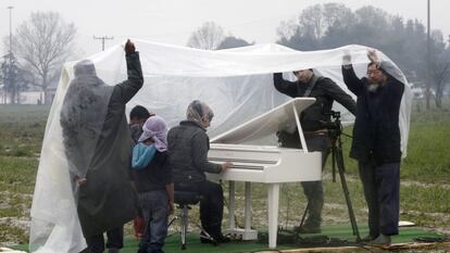 O artista Ai Weiwei (à direita) assiste à apresentação de piano da síria Nour Al Khizam no campo de refugiados situado na fronteira da Grécia com a Macedônia em 12 de março.