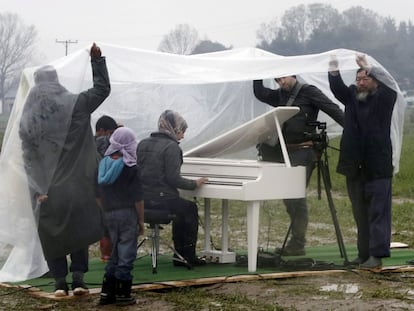 O artista Ai Weiwei (à direita) assiste à apresentação de piano da síria Nour Al Khizam no campo de refugiados situado na fronteira da Grécia com a Macedônia em 12 de março.