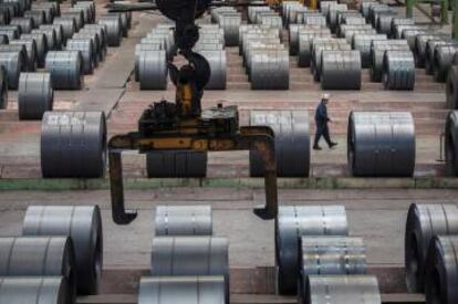 Un trabajador camina junto a rollos de acero en una fábrica de hierro y acero de Changshou (Chongqing, China).