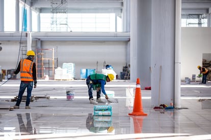 Un albañil hace trabajos en el piso de la terminal 1 del aeropuerto.