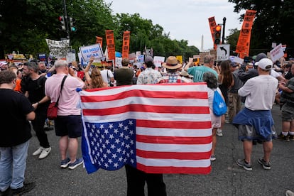 Un manifestante porta una bandera de Estados Unidos al revés durante una protesta por el desfile de este sábado.