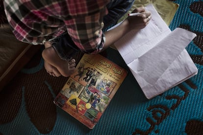 Hamzeh Al Ahmad se sienta en el suelo y escribe en un cuaderno durante una visita del psicólogo de Médicos Sin Fronteras a la tienda en la que vive con su familia en el Valle de la Bekaa (Líbano).