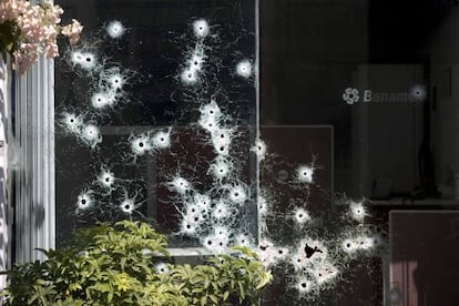 La ventana de un banco muestra orificios de bala en Apatzingán.