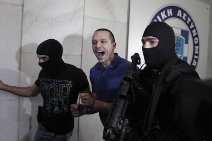 El portavoz y diputado de la ultra-derechista partido Aurora Dorada, Ilias Kasidiaris (C), grita a los periodistas, escoltado por policías.