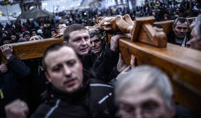 Un grupo de hombres cargan una pesada cruz durante una precesión en la plaza de la Independencia en Kiev (Ucrania).