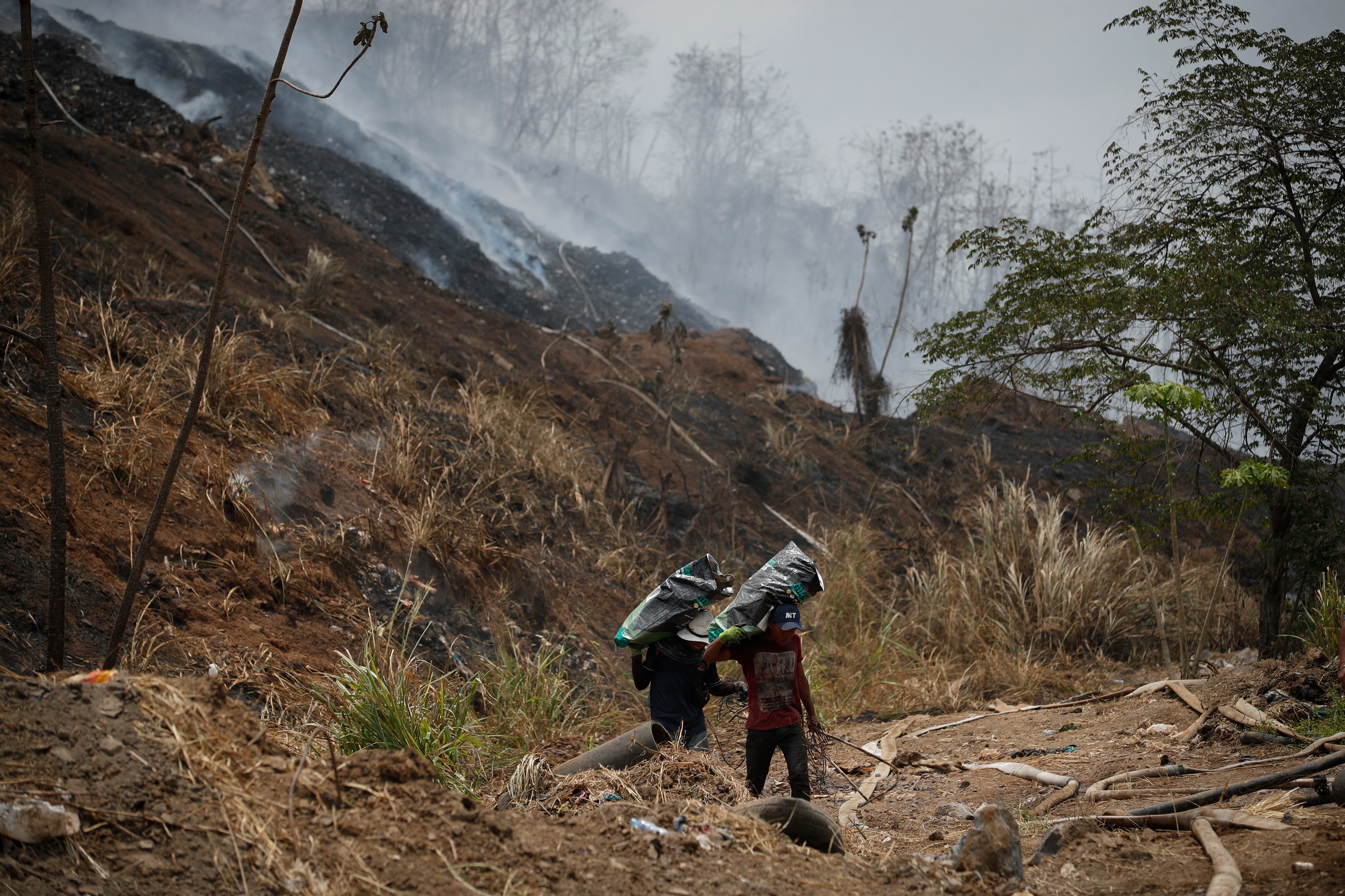 Recolectores de latas caminan en el vertedero de basura Cerro Patacón, afectado por un incendio, en Ciudad de Panamá, en marzo de 2024.