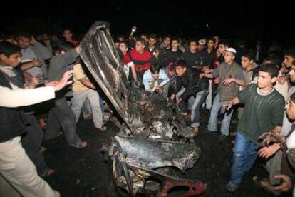 Jóvenes palestinos mueven los restos del vehículo alcanzado por misiles israelíes anoche en Gaza.