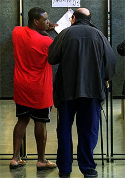 Dos votantes consultan el censo en un colegio electoral.