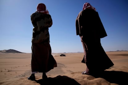 Dos hombres observan el paso de un coche durante la segunda etapa del Dakar.