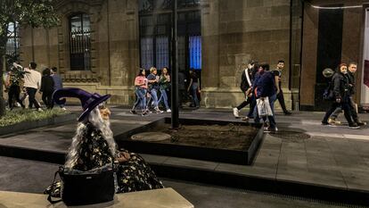 Una mujer con disfraz de bruja espera sobre la calle 20 de noviembre. El Gobierno de Ciudad de México organizó una verbena popular con música y ofrendas en las calles del Centro Histórico.