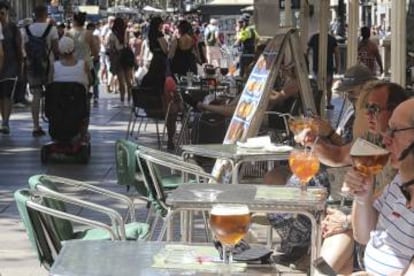 Varios turistas sentados en una terraza de La Rambla.