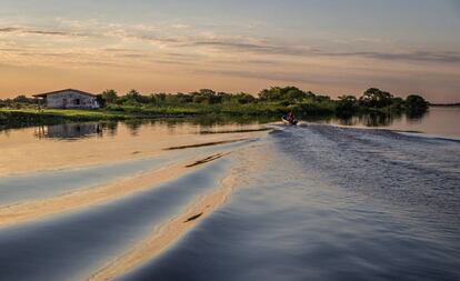 Una barca navegando al atardecer por el río Paraguay.