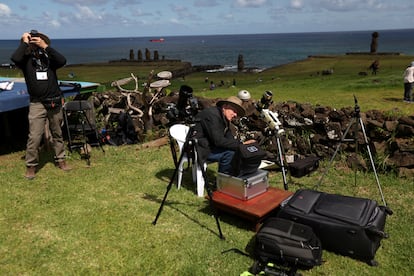 Personas preparan sus telescopios para observar el eclipse solar desde el área del monumento arqueológico Tahai en el parque nacional Rapa Nui, en Isla de Pascua, Chile.