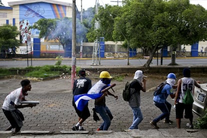 Varios manifestantes tratan de protegerse durante los enfrentamientos contra la policía, en Managua.