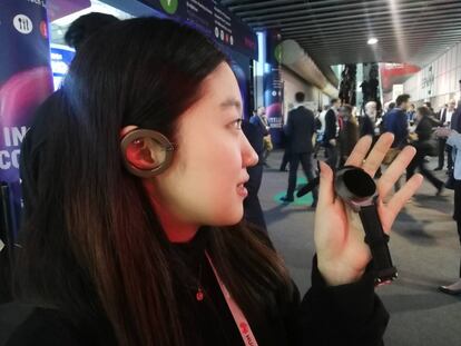 Una chica se pone de auricular la caja de un reloj inteligente.