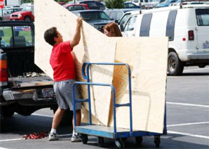 Un vecino de Carolina del Norte carga tablones en un coche para proteger su vivienda.