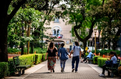 Tres jóvenes pasean por un parque cogidos de las manos.