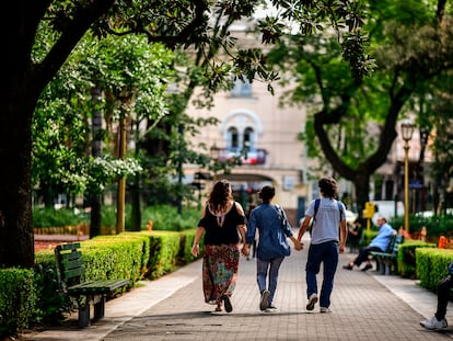 Tres jóvenes pasean por un parque cogidos de las manos.