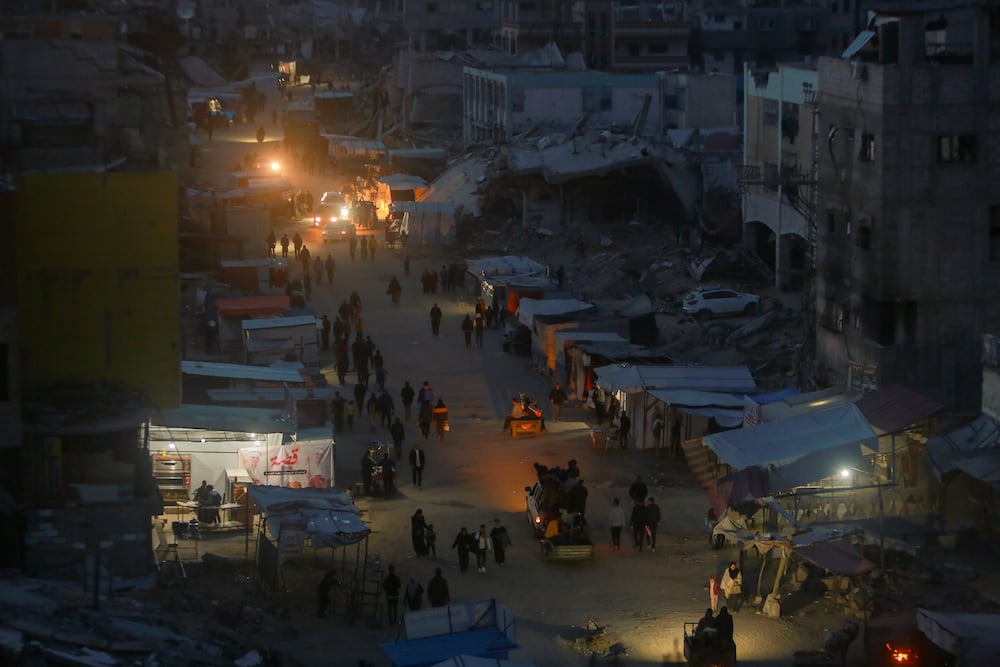 Palestinians walk along a central street at dusk in Khan Younis, central Gaza Strip, Saturday Jan. 18, 2025.(AP Photo/(AP Photo/Jehad Alshrafi)