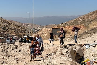 Mujeres con bebés a cuestas y padres con atados en la cabeza sortean el lunes el cráter que dejó un bombardeo israelí en el principal paso fronterizo entre el Líbano y Siria.