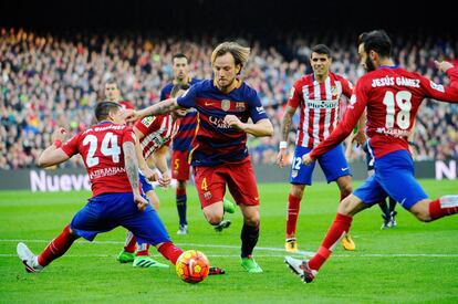 El jugador azulgrana, Rakitic, se lleva el balón entre varios jugadores del Atlético
