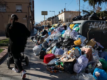 Una mujer pasa junto a una montaña de bolsas de basura acumuladas en una calle del centro de Salt.