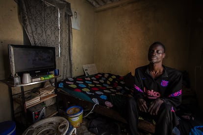 Mohamed Diop, de 40 años, sentado en la cama de su modesta habitación, en el barrio de Yoff Nbenguene. Padece una neuropatía congénita que le dificulta el movimiento, al igual que su hermano Abdul Aziz. Le encantan los documentales de animales y ver fútbol en la televisión. Cada día intenta caminar un poco por los alrededores de su casa, pero la pérdida de masa muscular en piernas y brazos le complican la tarea.