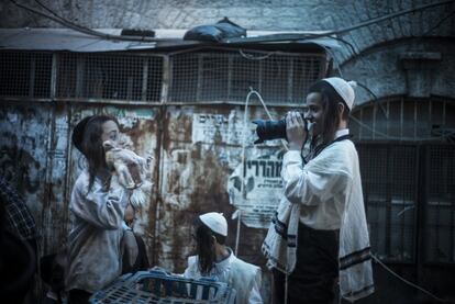 Un niño ultraortodoxo juega con una cámara de fotos mientras vende pollos para el 'kaparot', ritual que forma parte de las celebraciones del 'Yom Kippur', el 10 de octubre de 2016 en Jerusalén (Israel).