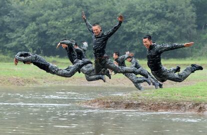 Unos soldados se lanzan sobre agua fangosa durante una sesión de entrenamiento militar en una zona de montaña en Heifei (China).