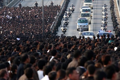 Miles de personas observan llegar el convoy con el féretro con los restos mortales del retrato del rey Bhumibol de Tailandia, durante su procesión de trasladado desde el hospital de Bangkok, donde falleció ayer a los 88 años, hasta el palacio real, en Tailandia.
