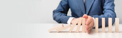 Business risk, crisis effect. Businessman protect falling domino with hand