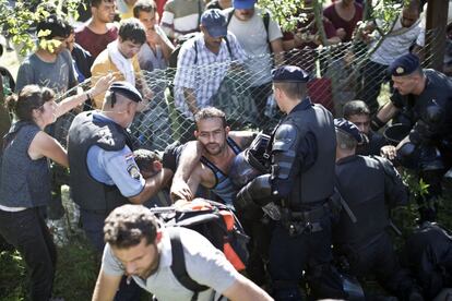 Los refugiados gritan "libertad" y "paso libre" y la Policía ha reforzado su presencia en la zona. En la imagen, varias personas atraviesan una valla en Tovarnik (Croacia).