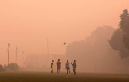 Un grupo de jóvenes juegan al fútbol en un día con una densa niebla, en Nueva Delhi, India.