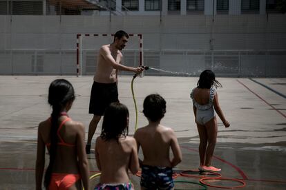 Un profesor refresca a alumnos en una escuela de Barcelona, el pasado mes de junio durante la ola de calor.