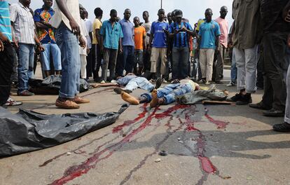 Seguidores de Alassane Ouattara rodean dos cadáveres de dos manifestantes muertos a manos de la policía leal al presidente Laurent Gbagbo.