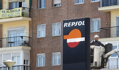 Un operario trabaja en un panel de Repsol en una gasolinera de Madrid.