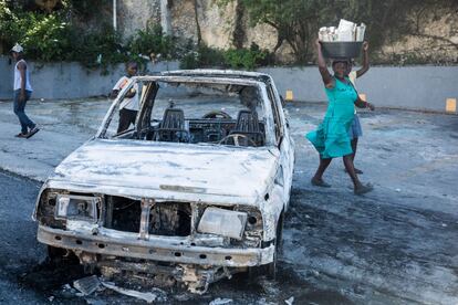 Dos mujeres frente a un coche quemado frente a la Embajada de Canadá en Puerto Príncipe. Varios cientos de policías y simpatizantes se manifestaron en la capital de Haití exigiendo mejores salarios.