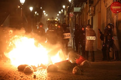 Contenedores incendiados frente a un cordón policial, en la calle Mesón de Paredes.