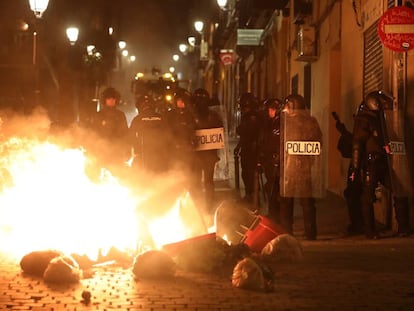 Contenedores incendiados frente a un cordón policial, en la calle Mesón de Paredes.