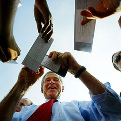 George W. Bush firma autógrafos durante su visita de campaña a una fábrica.