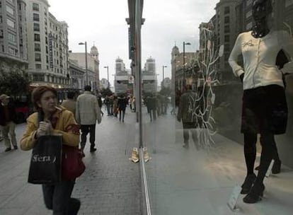 Una mujer observa un escaparate mientras camina por la Gran Vía.